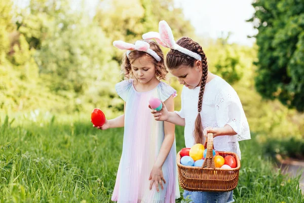 Group Of Children Wearing Bunny Ears Running To Pick Up colorful Egg On Easter Egg Hunt In Garden. — Stok Foto