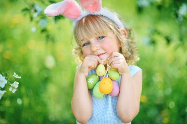 Paskalya yumurtaları ve bahçede tavşan kulakları ile sevimli komik kız. paskalya kavramı. Paskalya yumurtası avında gülen çocuk
