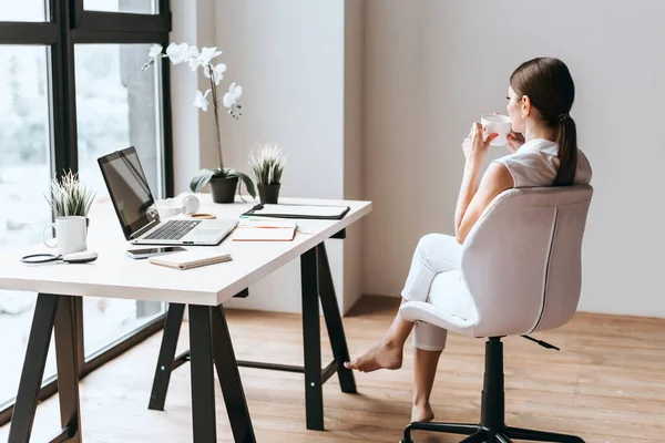 Werkende jonge zakenvrouw van thuis zitten op de vloer met laptop. — Stockfoto