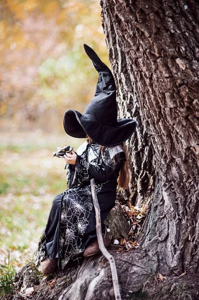 Mooie meisje heks. klein meisje in die kostuum vieren Halloween buiten en hebben een plezier. — Stockfoto