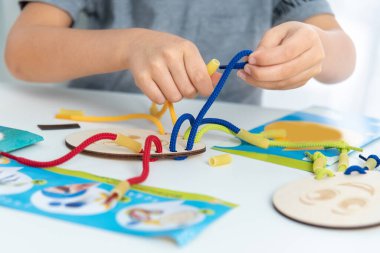 Dantel, ip ve makarna ile oynayan çocuk ellerini kapat. Kaliteli motor becerilerin gelişimi. Erken eğitim, Montessori Metodu. Bilişsel beceriler,