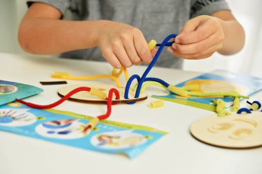 Dantel, ip ve makarna ile oynayan çocuk ellerini kapat. Kaliteli motor becerilerin gelişimi. Erken eğitim, Montessori Metodu. Bilişsel beceriler,