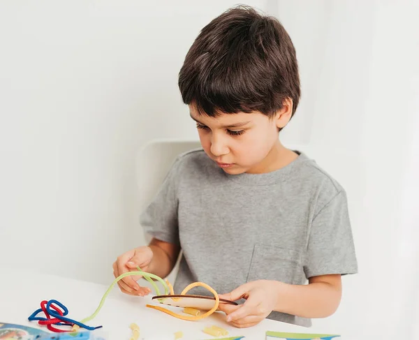 Gros plan des mains de l'enfant jouant avec de la dentelle ou de la corde et des pâtes. développement de la motricité fine. Early education, Montessori Method. Compétences cognitives , — Photo