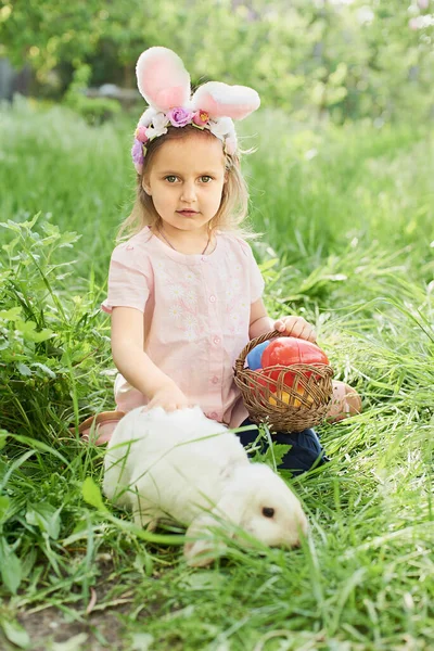 Baby with basket full of colorful eggs. Easter egg hunt. — Stock Photo, Image