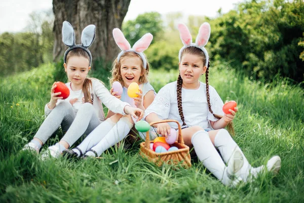 Grupa dzieci noszących królicze uszy biegnie odebrać kolorowe jajko na Easter Egg Hunt w ogrodzie. — Zdjęcie stockowe