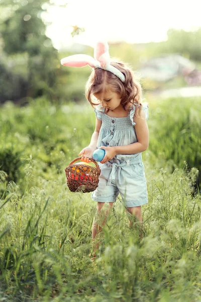 형형색색의 계란이 담긴 바구니를 가진 아기. 부활절 달걀찾기. — 스톡 사진