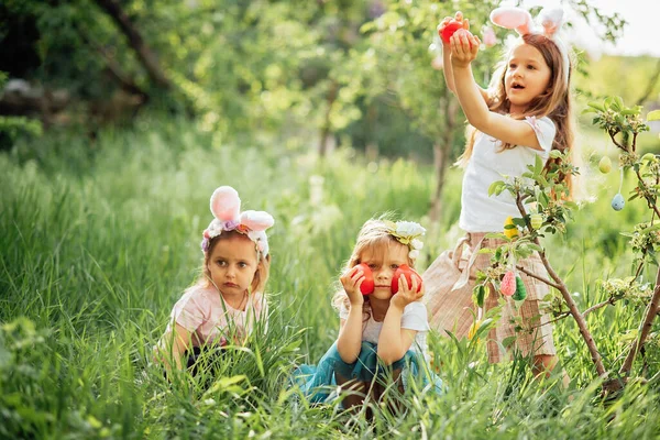 Group Of Children Wearing Bunny Ears Running To Pick Up colorful Egg On Easter Egg Hunt In Garden. — Stok Foto