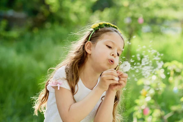 Menina soprando dente-de-leão flor foco seletivo. Época alérgica. — Fotografia de Stock