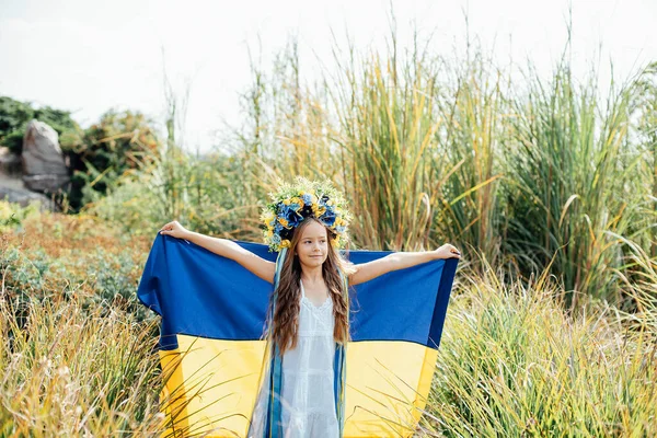 Ukrainian child girl in embroidered shirt vyshyvanka with yellow and blue flag of Ukraine in field. — Stock Photo, Image