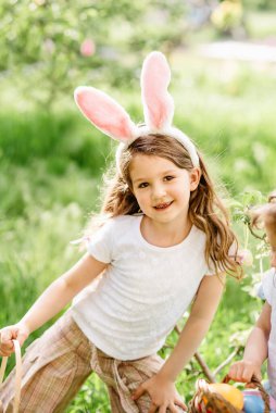 Sepeti renkli yumurtalarla dolu bir bebek. Paskalya yumurtası avı.