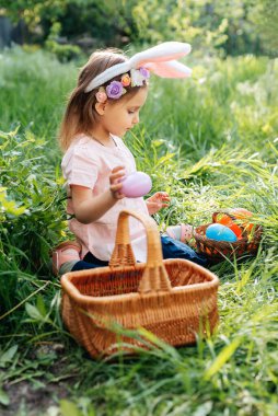 Sepeti renkli yumurtalarla dolu bir bebek. Paskalya yumurtası avı.