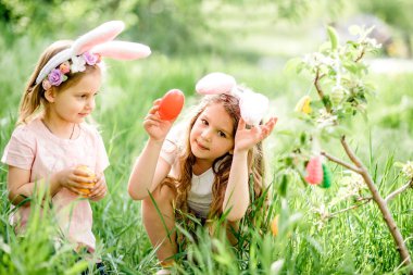 Bahçede Paskalya yumurtası avında renkli yumurta toplamak için koşan tavşan kulaklı bir grup çocuk. Paskalya geleneği