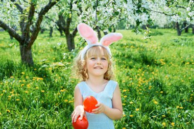 Sepeti renkli yumurtalarla dolu bir bebek. Paskalya yumurtası avı.