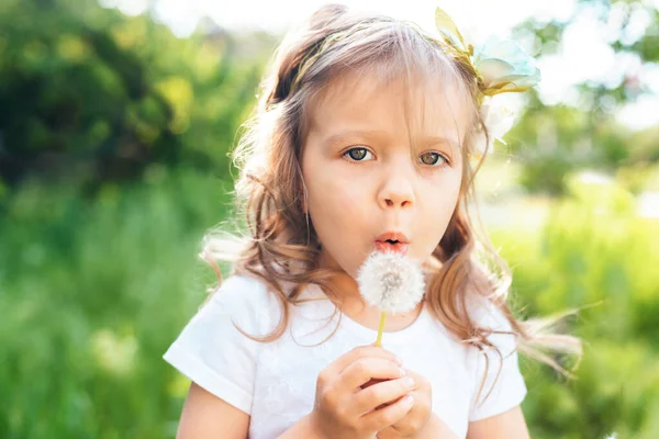 タンポポの花を吹いている女の子は選択的フォーカス。アレルギーシーズン. — ストック写真