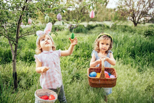 Grupa dzieci noszących królicze uszy biegnie odebrać kolorowe jajko na Easter Egg Hunt w ogrodzie. tradycja wielkanocna — Zdjęcie stockowe