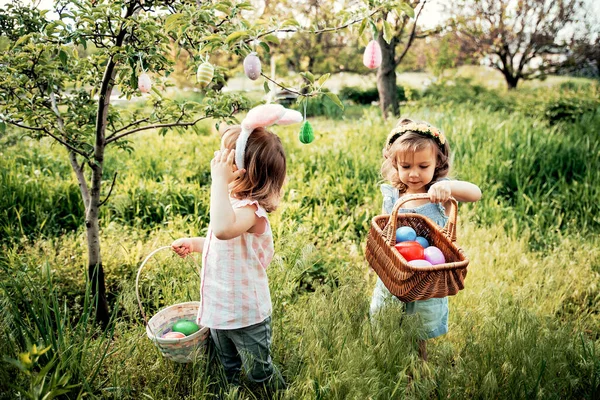 Group Of Children Wearing Bunny Ears Running To Pick Up colorful Egg On Easter Egg Hunt In Garden (dalam bahasa Inggris). Tradisi Paskah — Stok Foto