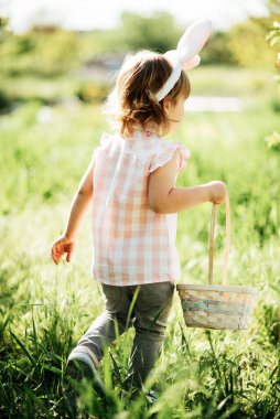 Sepeti renkli yumurtalarla dolu bir bebek. Paskalya yumurtası avı.