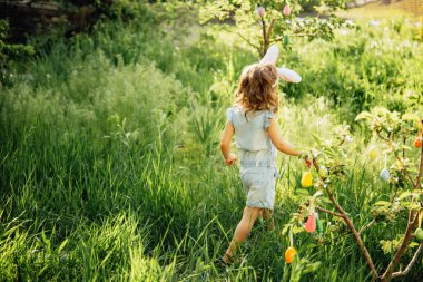 Sepeti renkli yumurtalarla dolu bir bebek. Paskalya yumurtası avı.