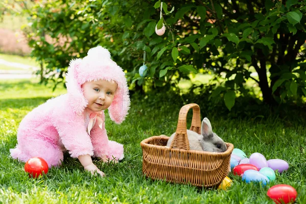 I bambini giocano con il coniglio vero. Bambino ridente a caccia di uova di Pasqua con coniglietto domestico . — Foto Stock
