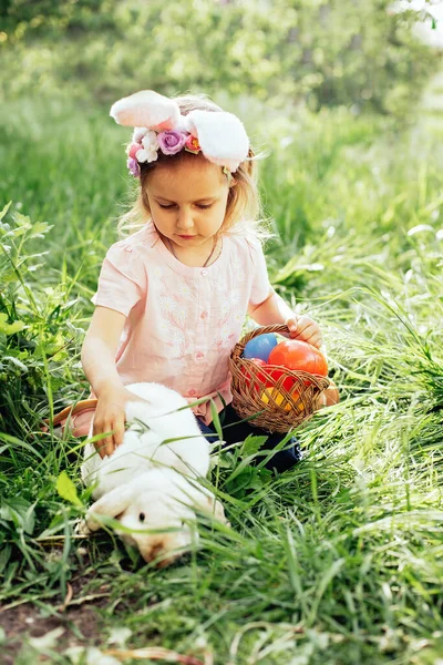 Дитина з кошиком, повним різнокольорових яєць. Полювання на великодні яйця . — стокове фото