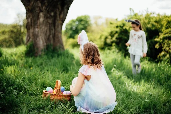 Skupina dětí na sobě Bunny uši běží vyzvednout barevné vejce na velikonoční vejce lov v zahradě. — Stock fotografie