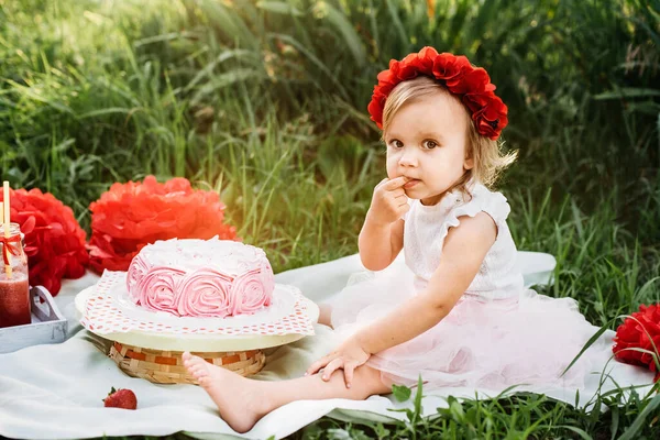 Deuxième anniversaire de la petite fille. Fille de deux ans assise près des décorations de célébration et de manger son gâteau d'anniversaire. Gâteau Smash . — Photo