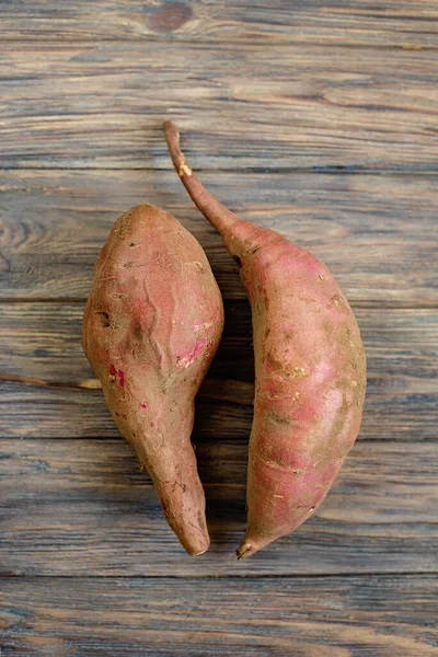 Raw sweet potatoes on wooden background top view. — Fotografia de Stock