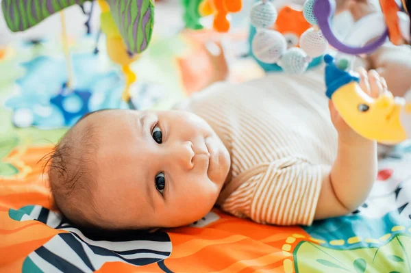 Baby ligt op ontwikkelend tapijt. spelen in Mobile. — Stockfoto