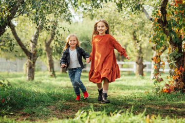 Çocuklar koşuyor, çayırda dans ediyorlar. Kızlar eğleniyor. Gün batımı parkında dans eden sevimli, uzun saçlı sarışın kız. Seçici odak