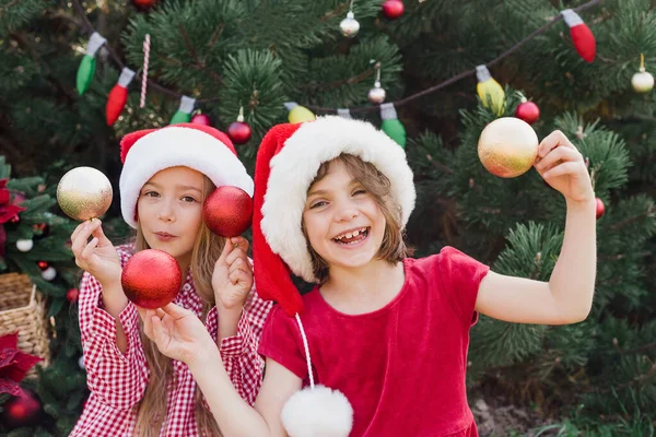 メリークリスマス サンタの2つの幸せな面白い子供たちの女の子の肖像画は 顔の近くにクリスマスのおもちゃと帽子 顔はない ハッピー ホリデー 妖精の魔法 休日を楽しむ幸せな子供たち — ストック写真