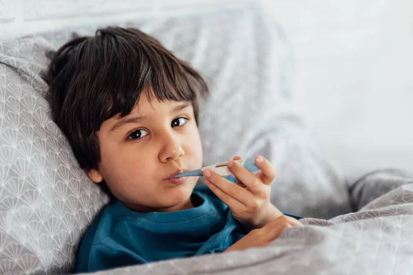 Child flu sick, boy with medical thermometer in mouth, health illness. Kid with cold rhinitis, get cold