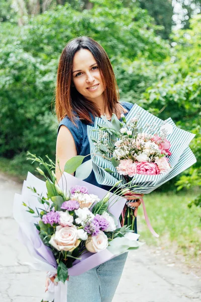 Woman florist with two delicate bouquets of different flowers as gift in boutiques of designer bouquets and premium flowers. Flower delivery and love. Birthday flower delivery best gift for woman.