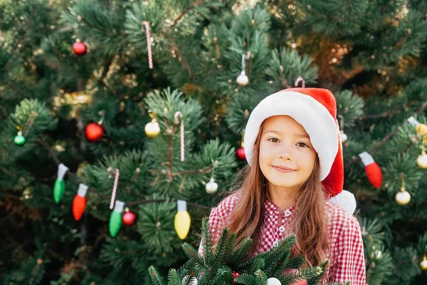 Merry Christmas. Portrait of happy funny child girls in Santa hat with Christmas wreath. Happy Holidays. Fairy Magic. Happy kid enjoying holiday. Christmas in July