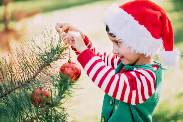 Christmas in july. Child waiting for Christmas in wood in summer. portrait of boy decorating christmas tree. winter holidays and people concept. Merry Christmas and Happy Holidays