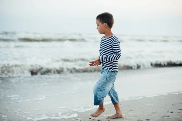 海辺の縞模様のTシャツの少年 海岸を走っている子供 夏休みだ 幸せな子供は日没時にビーチで遊んでいます — ストック写真