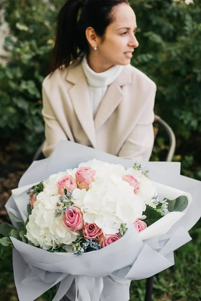 Woman holding flowers big bouquet white hydrangea flowers and pink roses. blooming flowers festive background, pastel and soft bouquet floral card. Mothers day, International Womens Day.