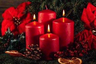 Ahşap arka planda üç yanan kırmızı renkli çelenk süslemesi. Noel 'den önceki bir gelenek. Noel arkaplan kavramlı xmas ışıkları. Şenlikli natürmort.
