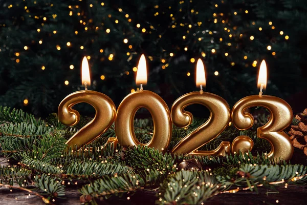 Holiday background Happy New Year 2023. Numbers of year 2023 made by gold burning candles on bokeh festive sparkling background. celebrating New Year holiday, close-up. Space for text