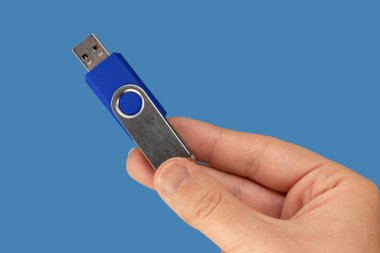 USB bellek aygıtı el ile mavi arka plan mavi. Önden Görünüm
