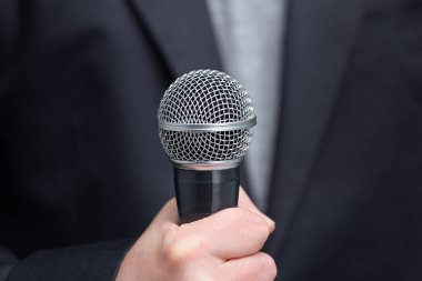 Görüşmeci veya muhabir olarak ön plan, elinde mikrofon ile mikrofon. Önden Görünüm