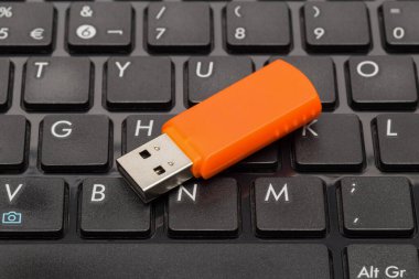 Siyah bir bilgisayar klavyesinde turuncu USB flash disk. Yakın plan.