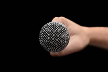 Mikrofon - Bir eliyle izole edilmiş siyah bir arkaplanda tutulan dinamik mikrofona yakın çekim. Profesyonel Sistem