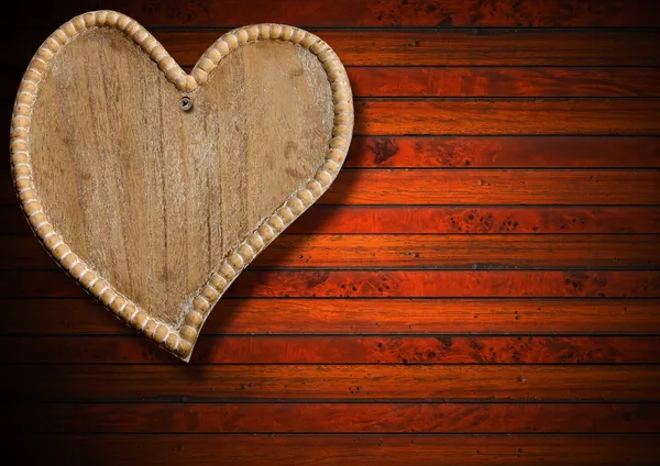 Dřevěné srdce na hnědé dřevěné pozadí — Stock fotografie