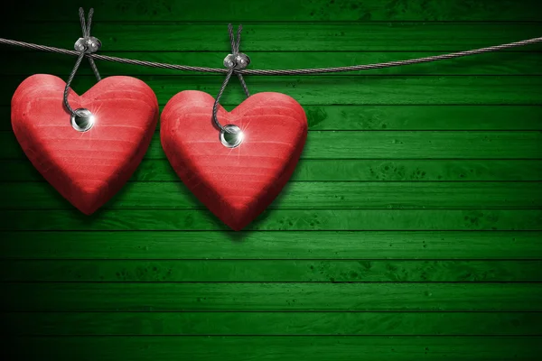 Rode houten harten op groene hout achtergrond — Stockfoto
