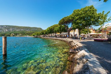 GARDA, İtalya - 26 Mayıs 2021 Garda şehir merkezi, Garda Gölü kıyısındaki köy ve turizm merkezi (Lago di Garda). Göl kıyısı boyunca gezinti güvertesi ve banklar. Verona ili, Veneto, İtalya, Avrupa