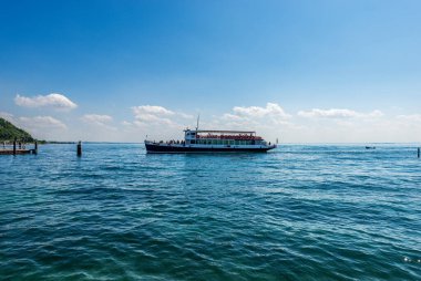 Feribot Garda kasabasının küçük limanında hareket ediyor. Garda Gölü kıyısındaki turizm beldesi (Lago di Garda), Verona, Veneto, İtalya, Güney Avrupa.