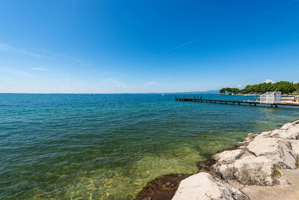 Verona ili, Veneto, İtalya ve Güney Avrupa 'da küçük bir köy olan Bardolino' nun önünde Garda Gölü 'nde (Lago di Garda) küçük boş ahşap iskelesi olan güzel bir sahil..