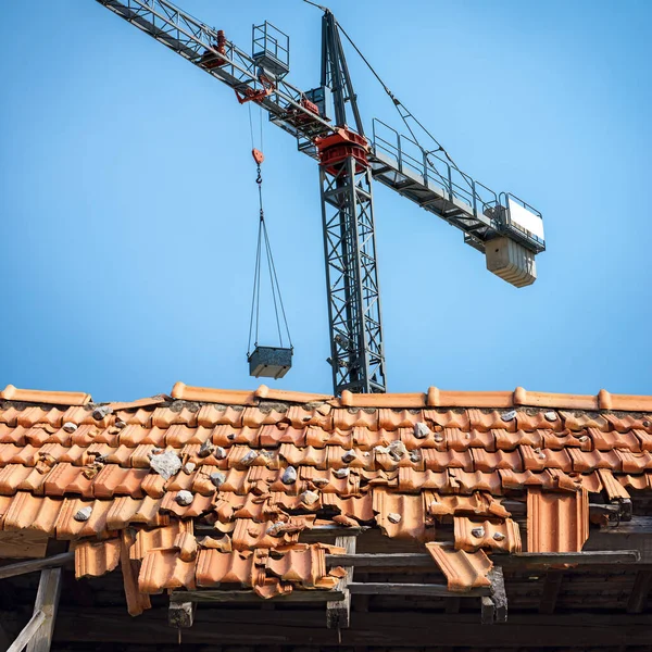 Grauer Kran Und Nahaufnahme Eines Beschädigten Daches Mit Orangefarbenen Ziegeln — Stockfoto