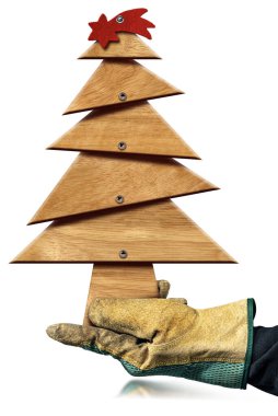Koruyucu iş eldivenleriyle el, beyaz arka planda izole edilmiş kırmızı kuyrukluyıldızlı küçük ahşap bir Noel ağacı tutuyor..
