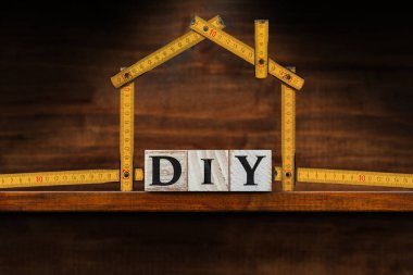 Ahşap bloklardan (kendin yap) yapılmış DIY metninin ve kopya alanı olan ahşap tezgahta ev şeklinde katlanmış bir cetvel..